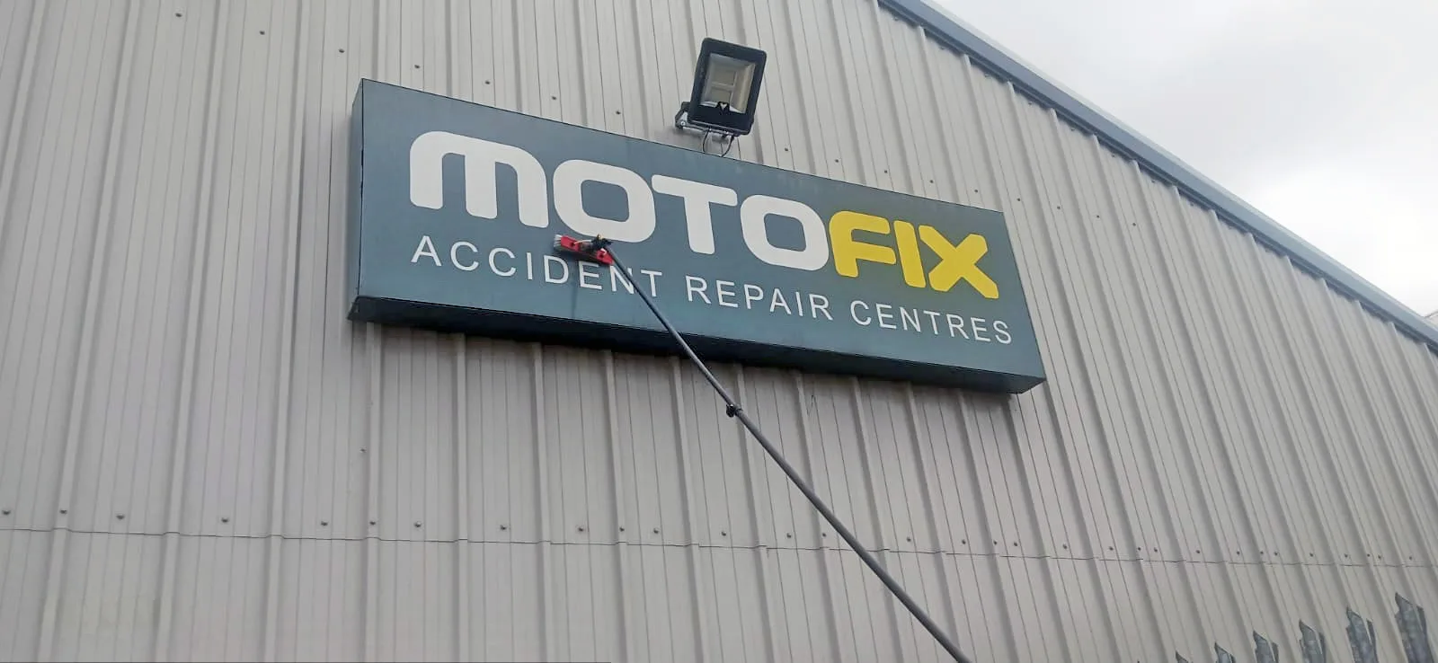 Telescopic pole cladding cleaning on commercial building exterior