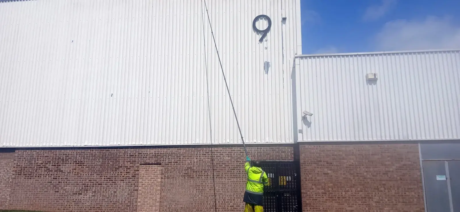 Technician cleaning warehouse cladding with extendable pole - AJB Group, Corby