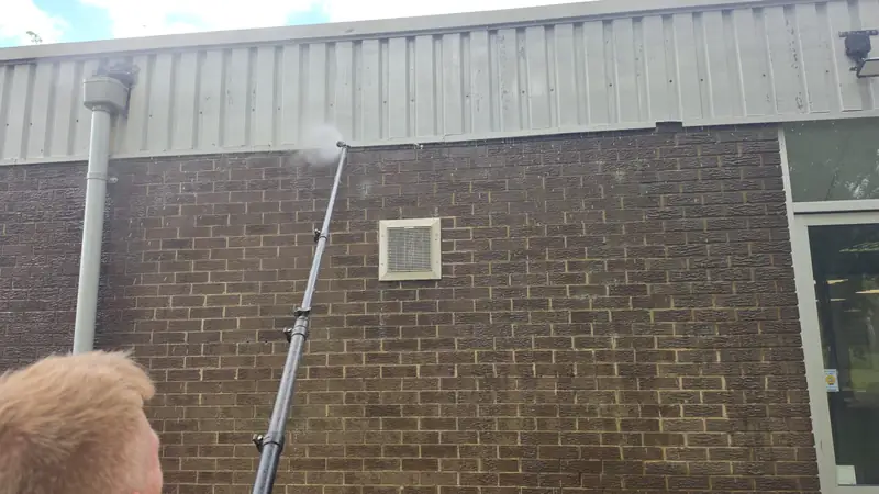 Operator cleaning vent grille brick wall, Northampton.