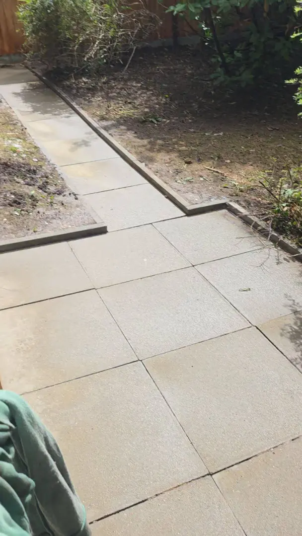 During - natural stone patio slabs being jet washed, dirty-to-clean contrast, Luton.