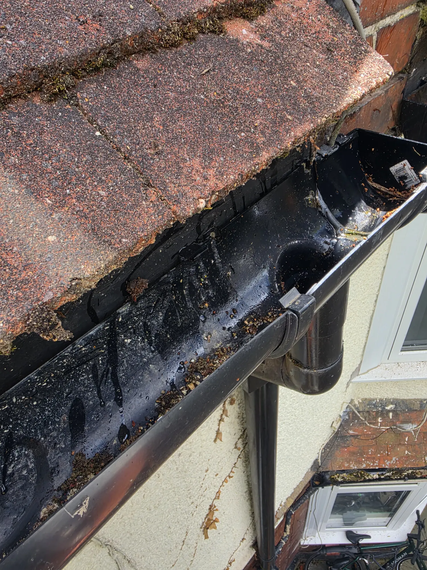 Before - black gutter blocked with moss and debris, Luton.